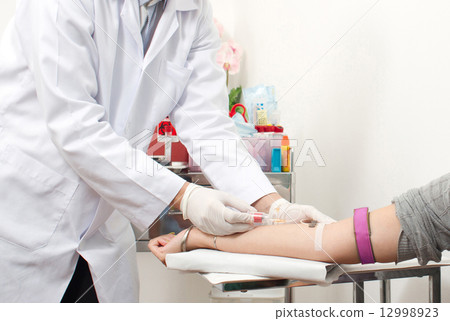 doctor with syringe is taking blood 12998923