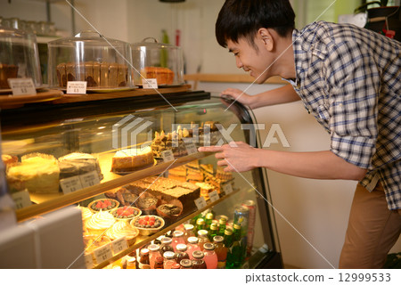 Man choosing desserts at a cafe 12999533
