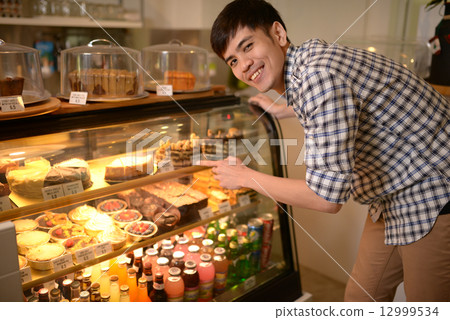 Man choosing desserts at a cafe 12999534
