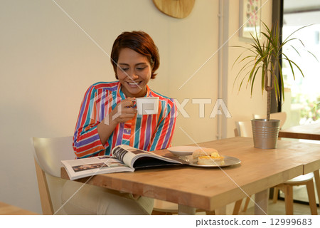 Woman reading magazine at cafe 12999683
