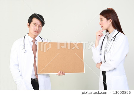 Male doctor holding signboard and female doctor looking with interest 13000896