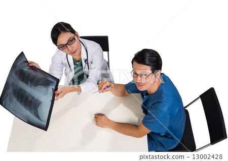 Surgeon and medical doctor discussing whilst referring to X-ray film Surgeon and medical doctor discussing whilst referring to X-ray film 13002428