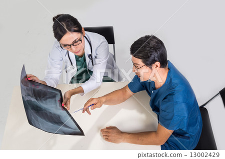 Surgeon and medical doctor discussing whilst referring to x-ray film Surgeon and medical doctor discussing whilst referring to x-ray film 13002429