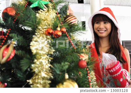 A beautiful Asian lady dressed with Santa Hat dressing up Christmas tree in parapation for Christmas A beautiful Asian lady dressed with Santa Hat dressing up Christmas tree in parapation for Christmas 13003128