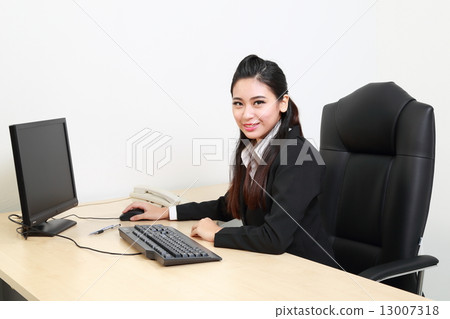 Female in suit at offce desk looking tward camera Female in suit at offce desk looking tward camera 13007318