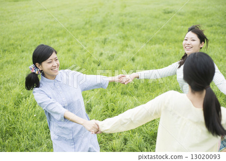 Three women holding hands in the meadow 13020093