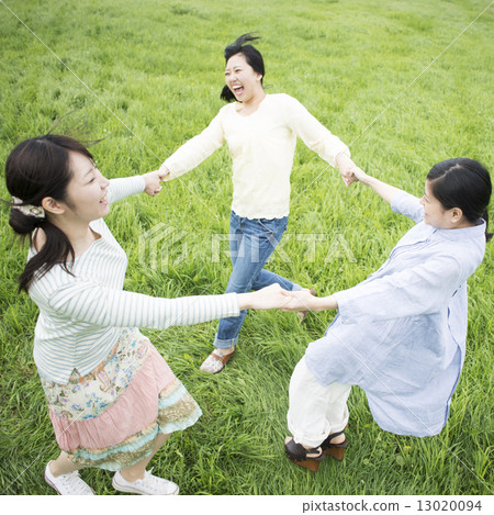 Three women holding hands in the meadow 13020094
