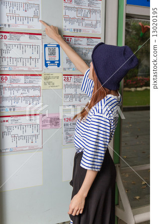 Woman at bus stop looking at timetable Woman at bus stop looking at timetable 13020195