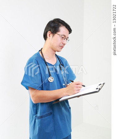 Male doctor in OT uniform writing report on clipboard 13021722