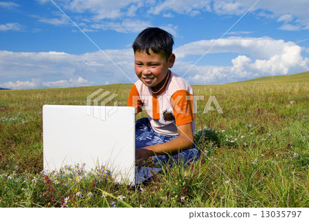 Mongolian Boy with Laptop on Grass 13035797