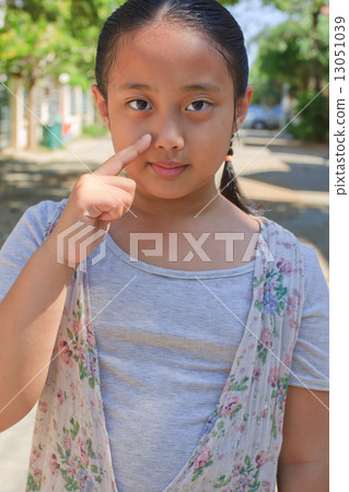 face of asian young girl standing and pointing to her nose 13051039