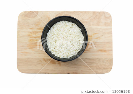 Uncooked rice in a bowl, on chopping block, isolated on white ba Uncooked rice in a bowl, on chopping block, isolated on white ba 13056198