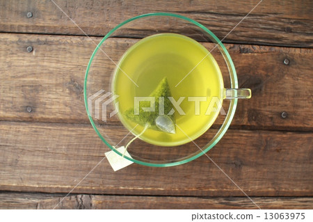 Hot green tea brewed in a triangular tea bag 13063975