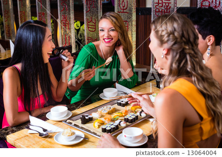 Young people eating sushi in Asian restaurant 13064004