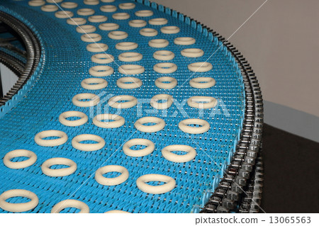 Crude forms of bagels on a conveyor. Crude forms of bagels on a conveyor. 13065563