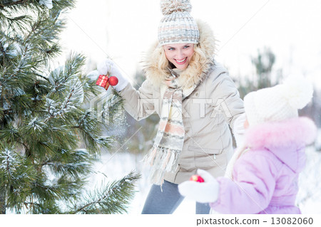 Happy mother and child playing with christmas tree decorations outdoor 13082060