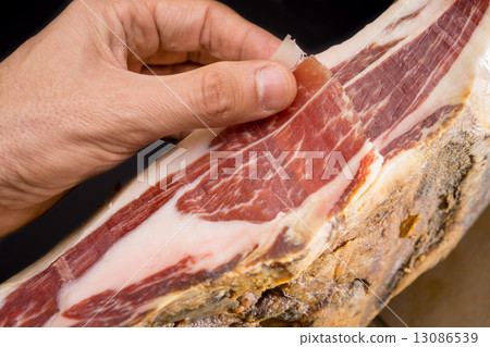 Top view of caucasian man hand over Serrano ham 13086539