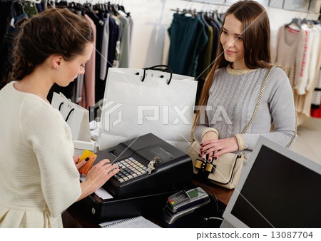 Happy woman customer paying with credit card in fashion showroom Happy woman customer paying with credit card in fashion showroom 13087704