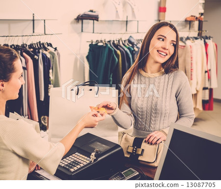 Happy woman customer paying with credit card in fashion showroom Happy woman customer paying with credit card in fashion showroom 13087705