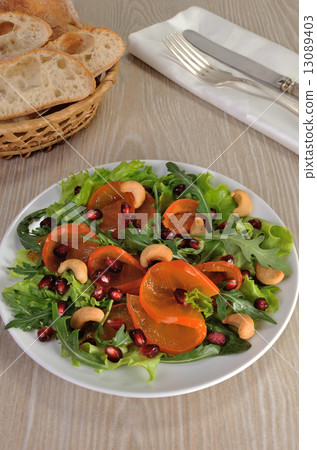 Salad greens with persimmon, pomegranate and cashews Salad greens with persimmon, pomegranate and cashews 13089403