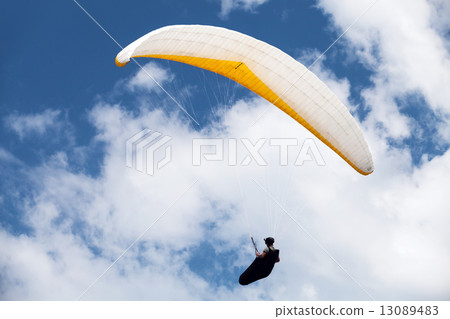 Paraglider in the blue cloudy sky 13089483