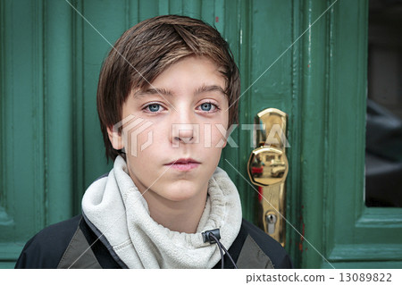 portrait of a beautiful teenage boy in front of a green door 13089822