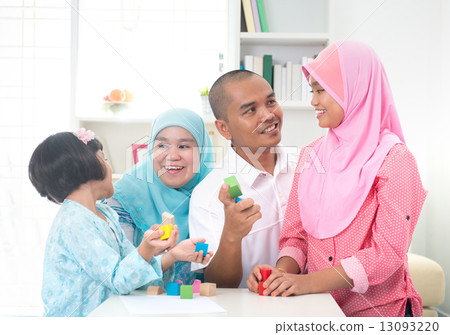 Malay family at home. Muslim girl building a wooden toy house. S Malay family at home. Muslim girl building a wooden toy house. S 13093220