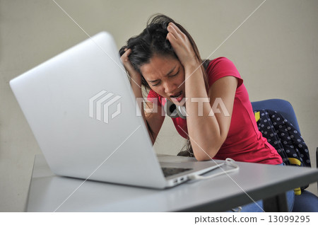 A young Asian female student feeling stressed over her school work / reseach in front of laptop A young Asian female student feeling stressed over her school work / reseach in front of laptop 13099295