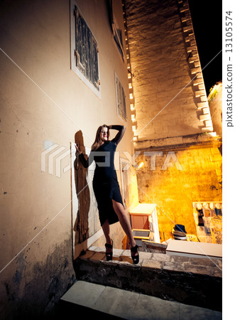 slim woman in black dress posing on street at night 13105574