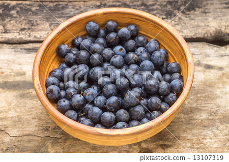 Ripe blackthorn berries in clay bowl on wood background 13107319