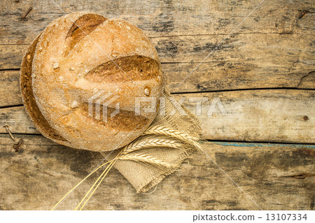 Loaf of whole wheat bread with ears on wood background 13107334