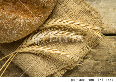 Loaf of whole wheat bread with ears on wood background 13107335