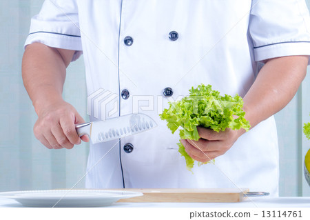 chef holding lettuce and knife in kichen 13114761