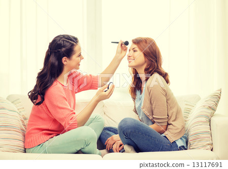 two smiling teenage girls applying make up at home two smiling teenage girls applying make up at home 13117691
