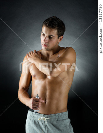 young male bodybuilder applying pain relief gel 13117750