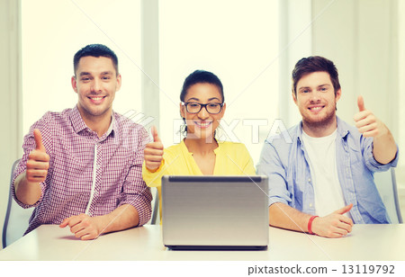 three smiling colleagues with laptop in office 13119792