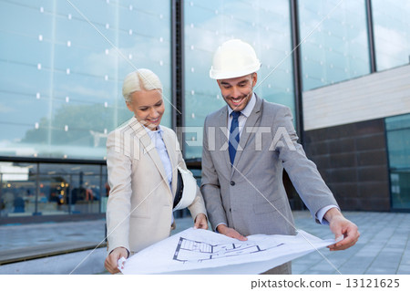 smiling businessmen with blueprint and helmets 13121625