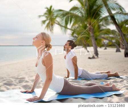 happy couple making yoga exercises on beach 13121660