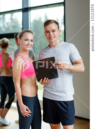 smiling young woman with personal trainer in gym smiling young woman with personal trainer in gym 13121974