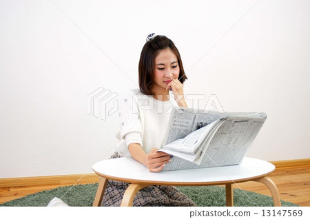 A young lady reading a newspaper 13147569