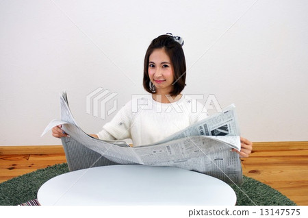 A young lady reading a newspaper 13147575