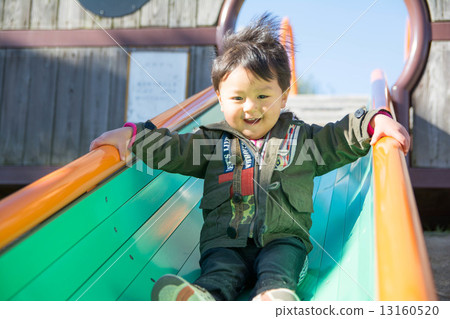 A boy playing on a slide in a park in winter A boy playing on a slide in a park in winter 13160520