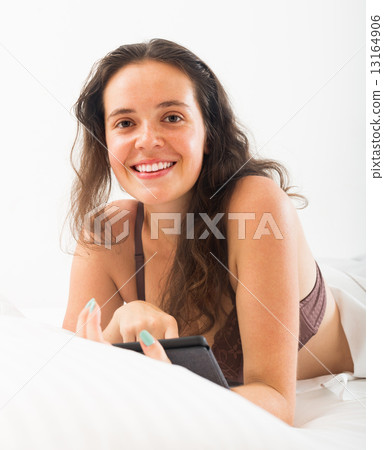 Woman with ereader lying in bed 13164906