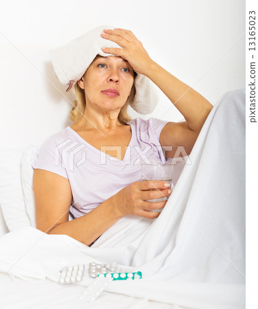 pensioner laying in bed with towel on forehead 13165023