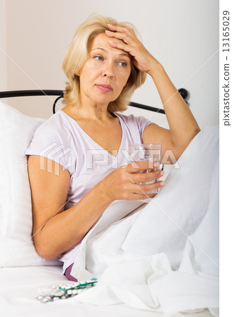 pensioner in bed with pills and glass of water 13165029