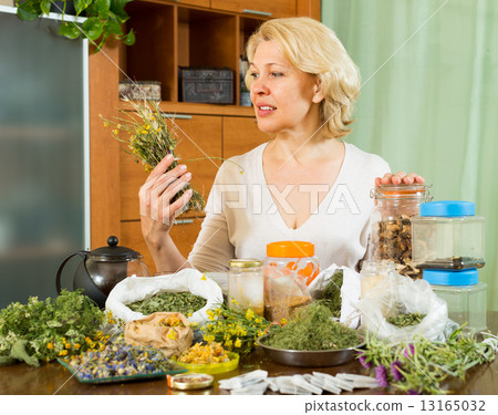 Mature woman with herbs at table 13165032
