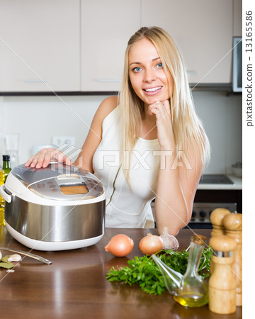 Woman cooking with multicooker Woman cooking with multicooker 13165586
