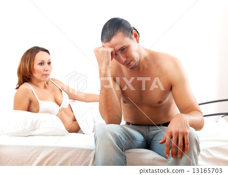 Sad man with problem in bed, woman consoling him on bed in bedro 13165703