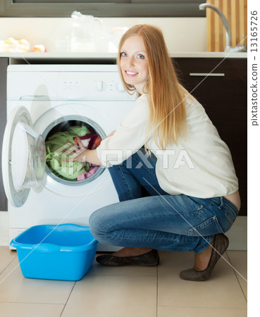 Long-haired woman using washing machine at home Long-haired woman using washing machine at home 13165726
