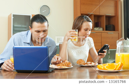 Couple using devices during breakfast Couple using devices during breakfast 13165766